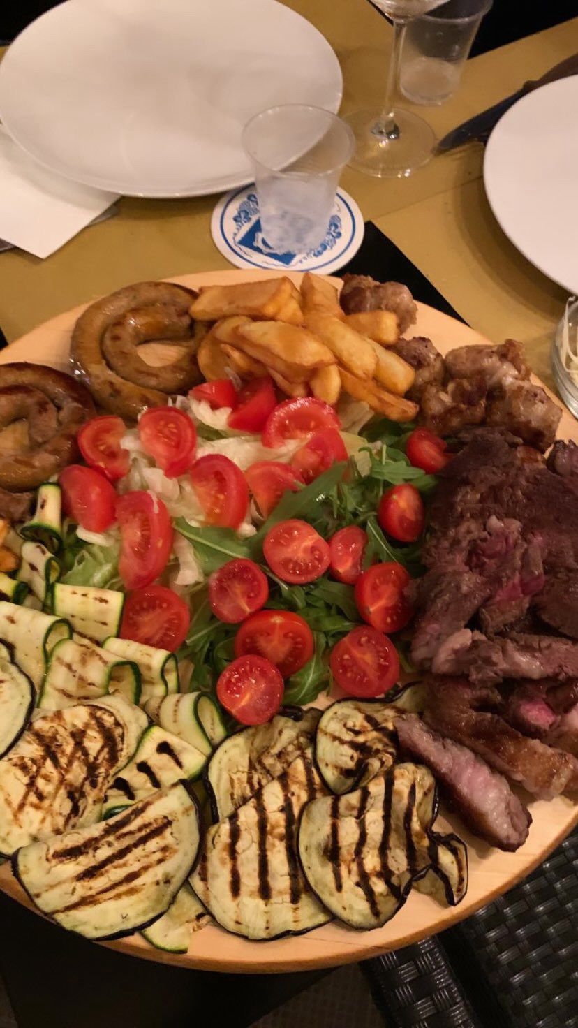 Tagliere di carne mista con tagliata, salsiccia, verdure grigliate e pomodorini